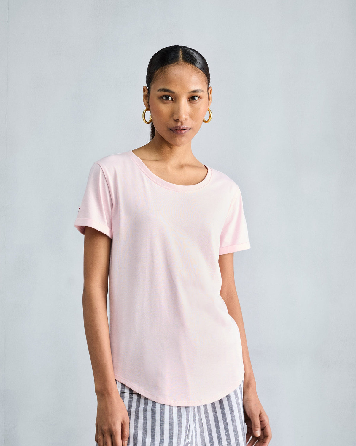 Person wearing the Basic T-Shirt in blush pink with a rounded hem.