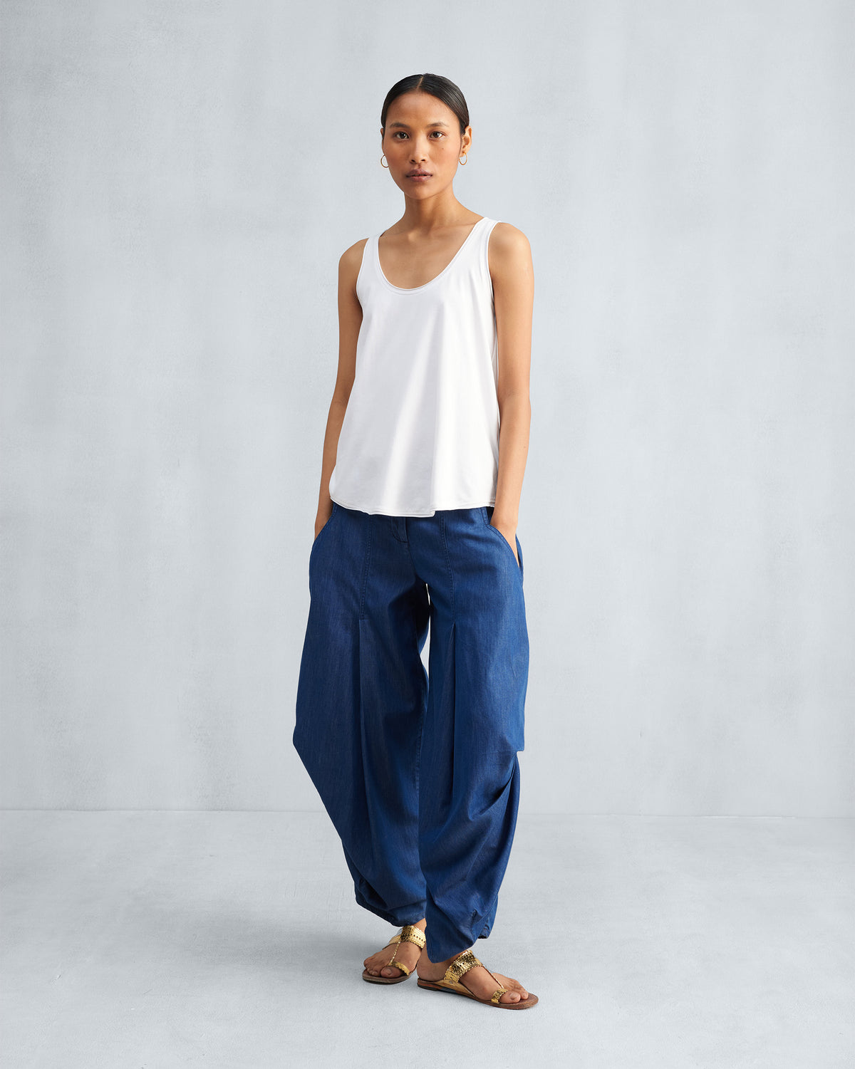 Person wearing a white Ukiyo tank with wide blue pants.