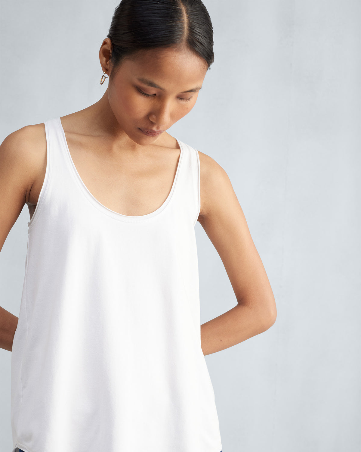 Person wearing a white Ukiyo tank with a wide scoop neck.