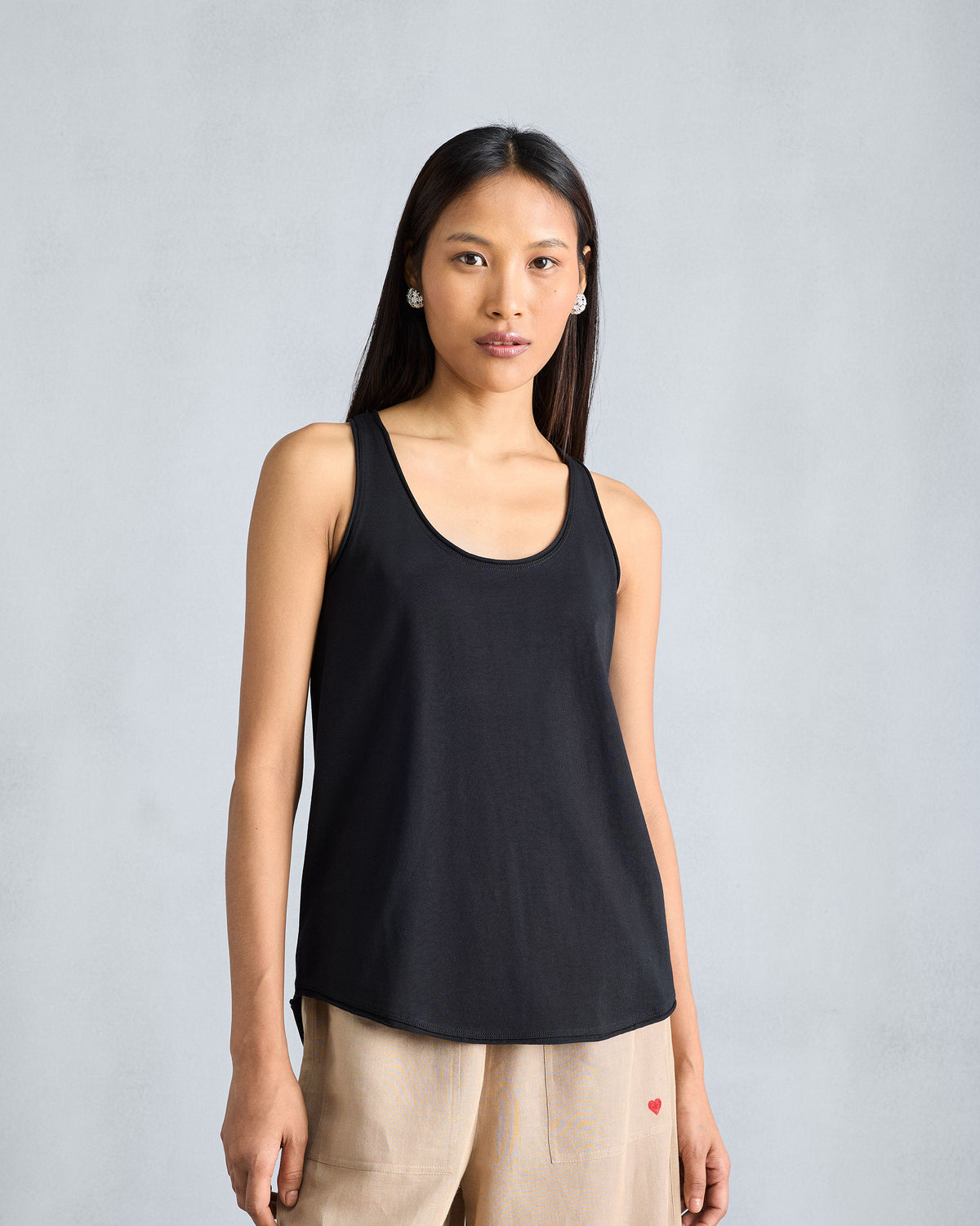 Person wearing a black Ukiyo tank with a deep scoop neck and hip hem.