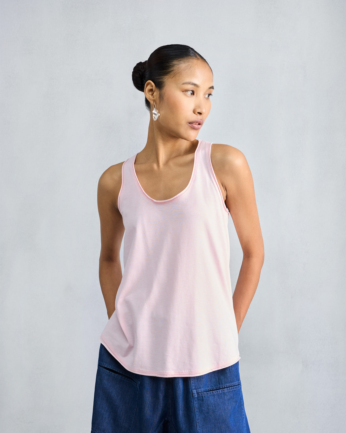 Person wearing a light pink Ukiyo tank with a soft flared hem.