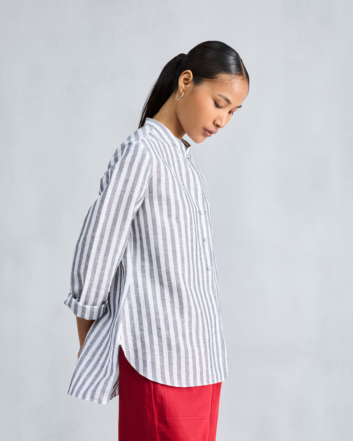 Side view of a charcoal striped mandarin collar top with a curved hem.