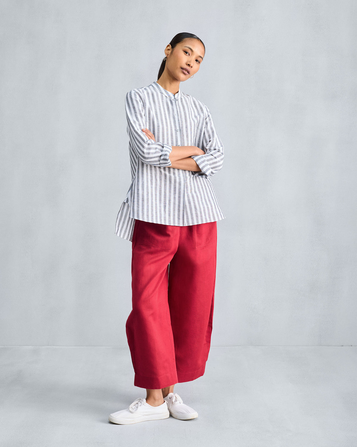 Person wearing a charcoal striped mandarin collar top with a high-low hem.