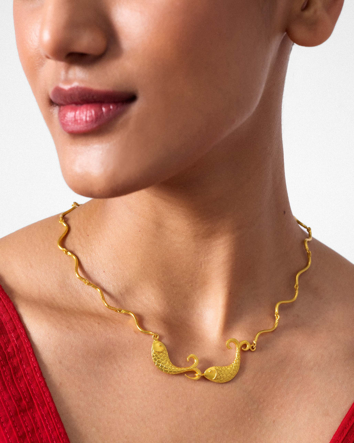 Close-up of twin fish on a gold Meen necklace.
