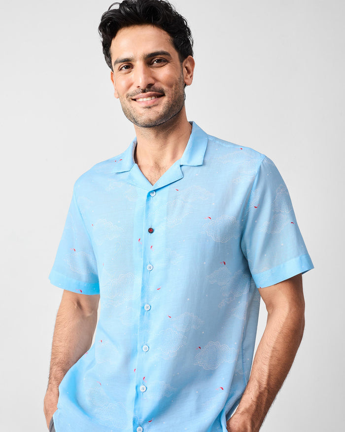 Person wearing a light blue Mistari Shirt with a white cloud print and red accents.