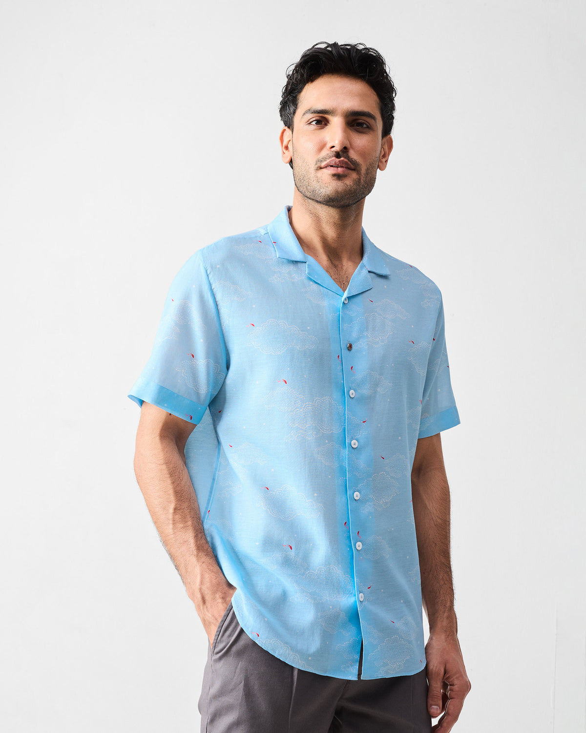 Person wearing a light blue Mistari Shirt with a camp collar and white cloud print.