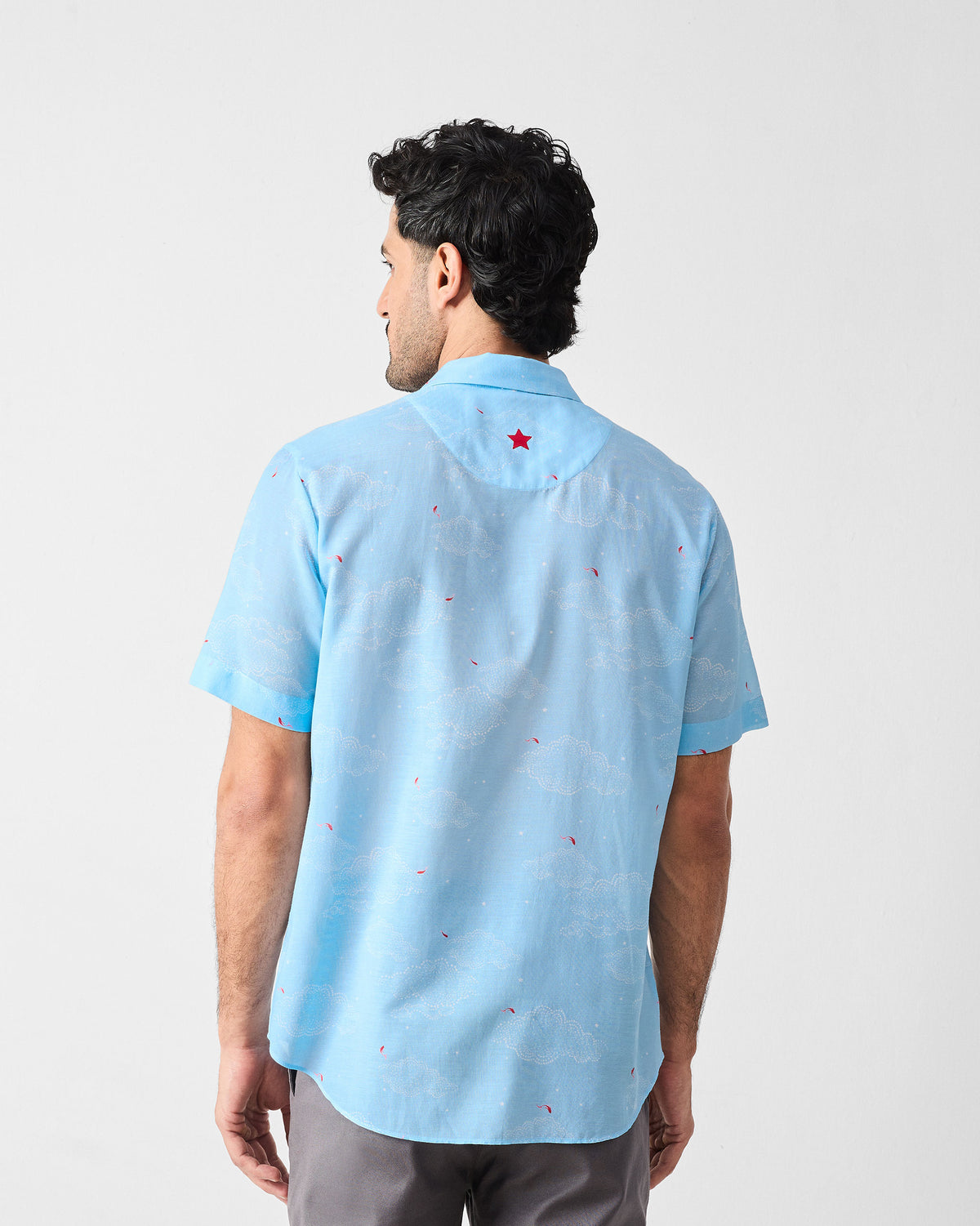 Back of a light blue Mistari Shirt with a white cloud print and a red embroidered star.
