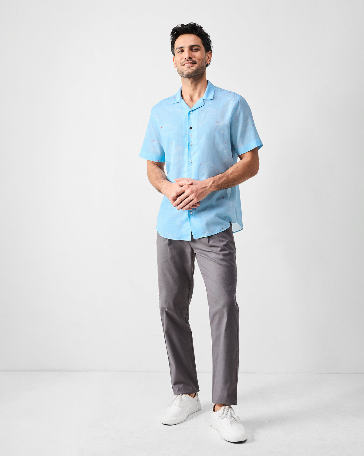 Person wearing a light blue Mistari Shirt with a camp collar and cloud print.