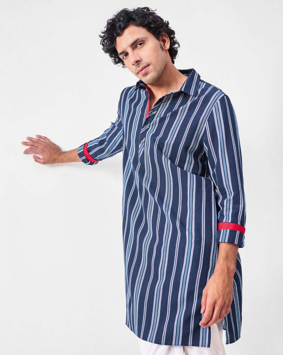 Person wearing a blue and navy striped Comoros kurta with red cuff lining.