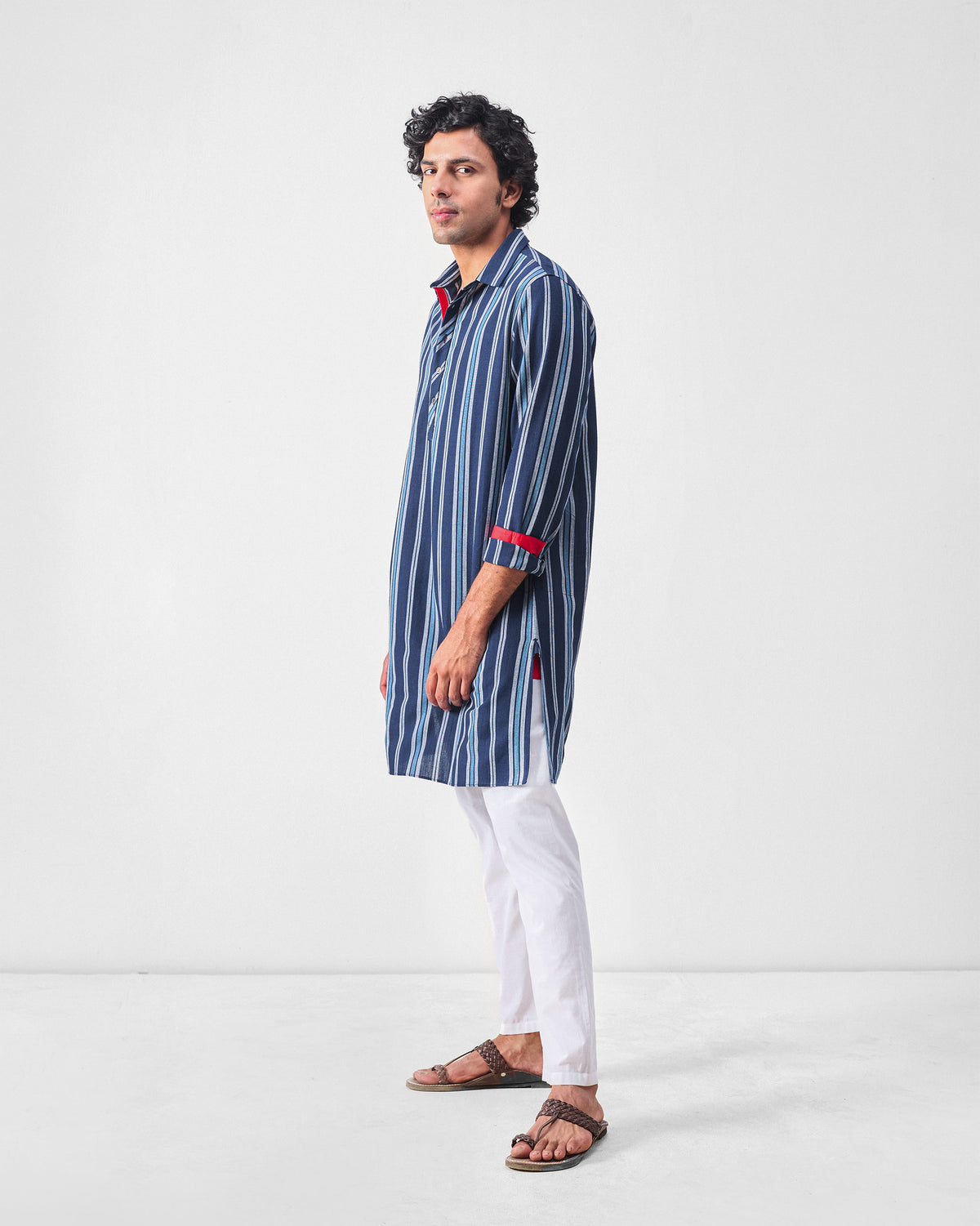 Side view of a blue and navy striped Comoros kurta with red cuff accents.