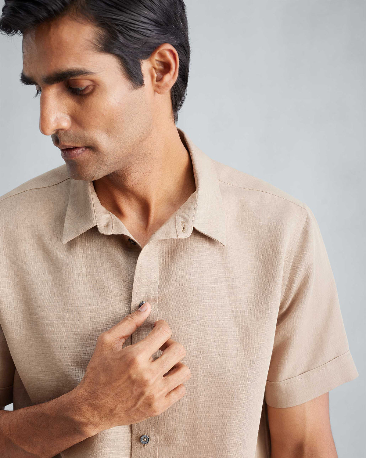 Close-up of the collar and short sleeve on a beige half-sleeve shirt.