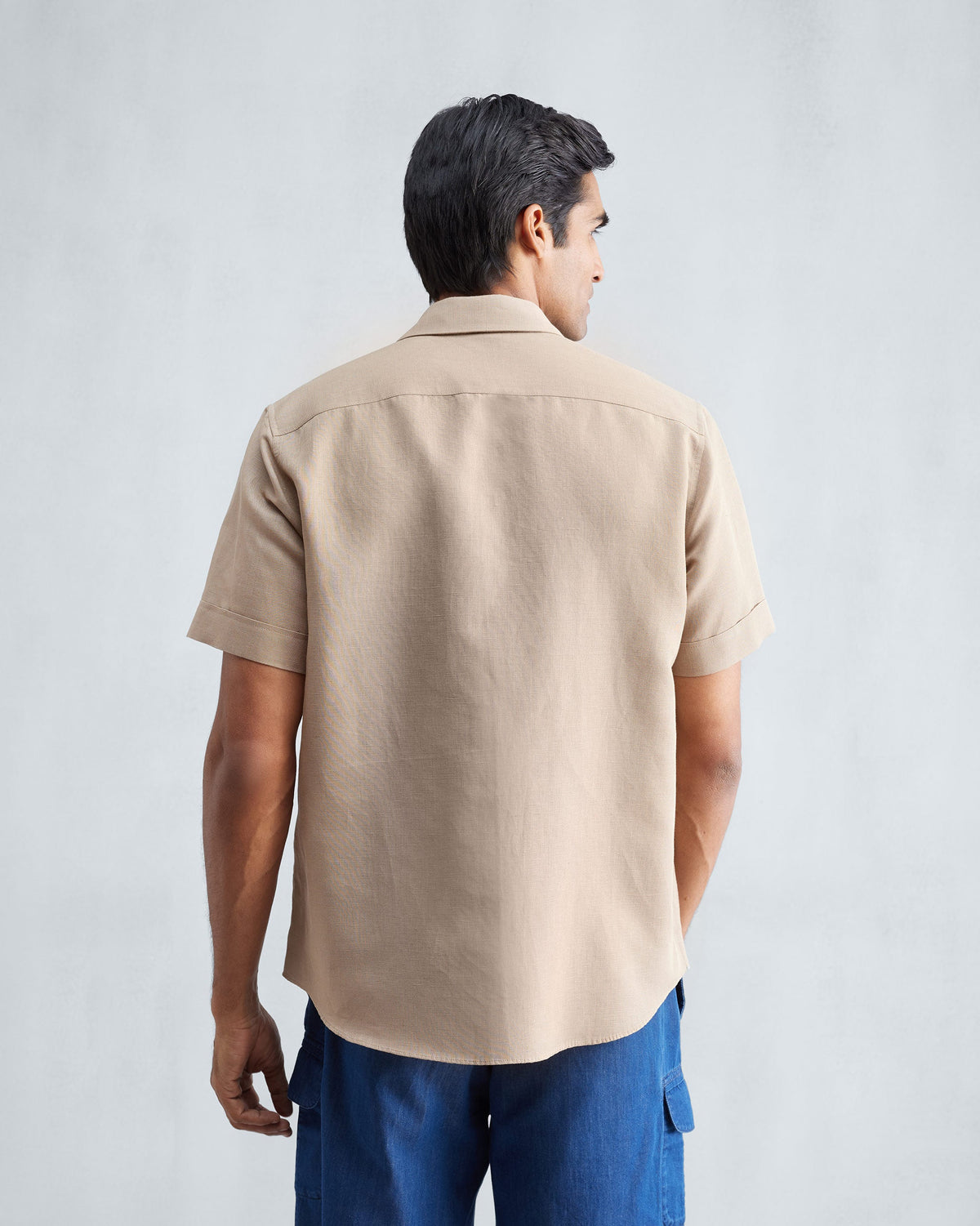 Back of a beige half sleeve shirt worn by a person.