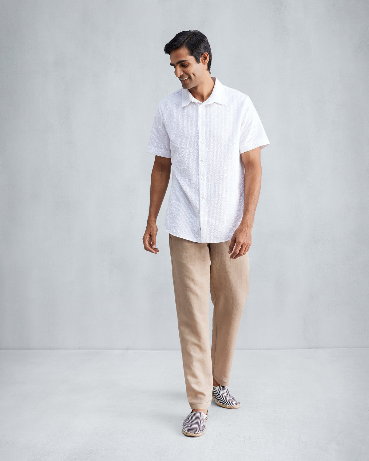 Person wearing a white half-sleeve seersucker shirt at full length.