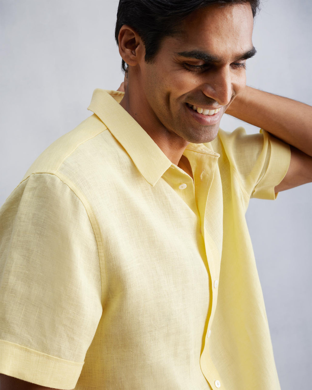 Person wearing a lemon linen half-sleeve shirt showing the collar and fabric.