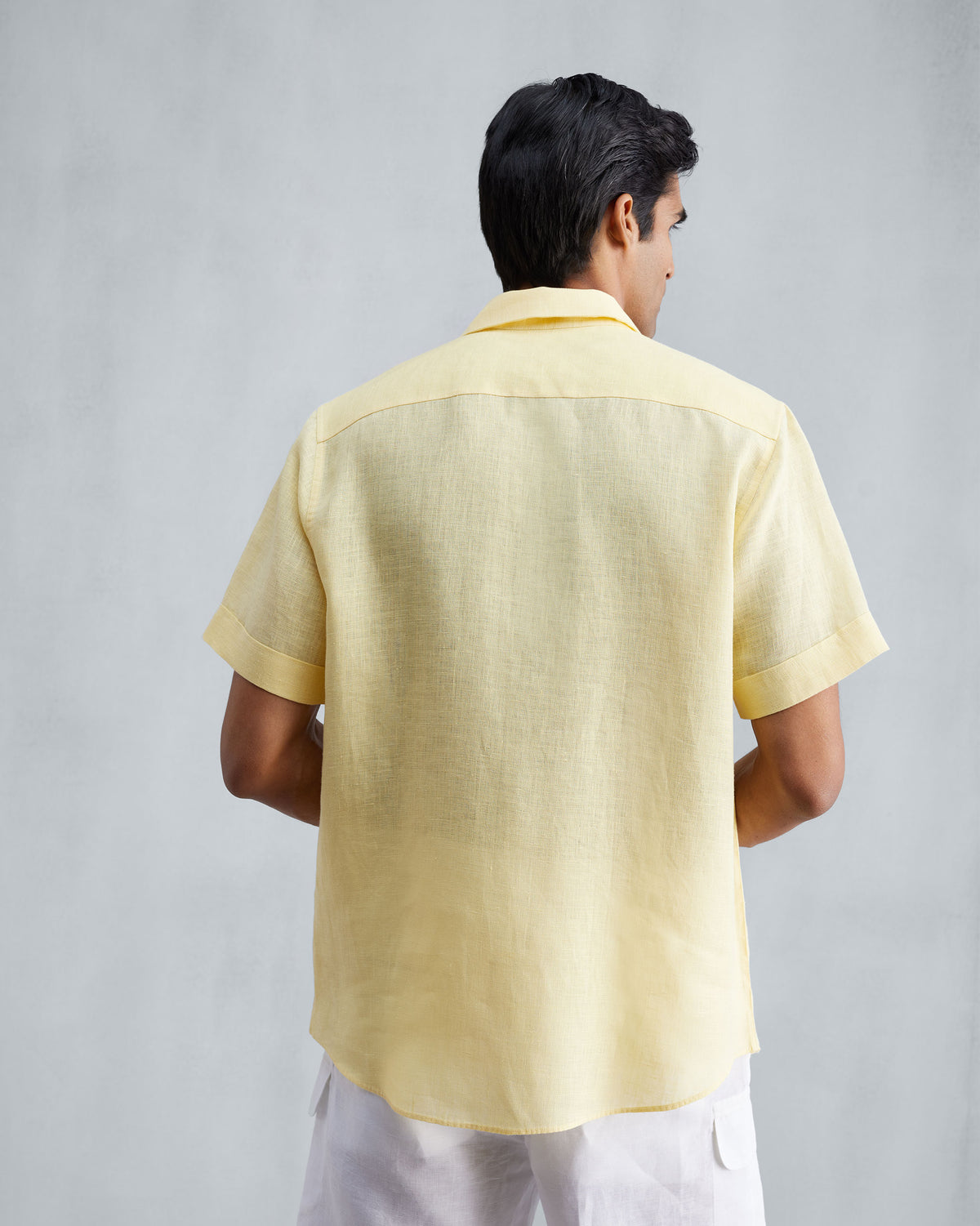 Back of a lemon linen half-sleeve shirt with a yoke and cuffed sleeves.
