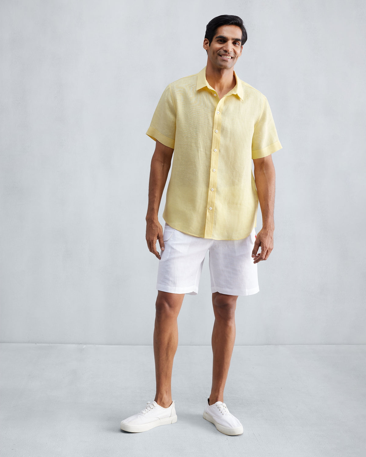 Person wearing a lemon half-sleeve linen shirt with a curved hem.