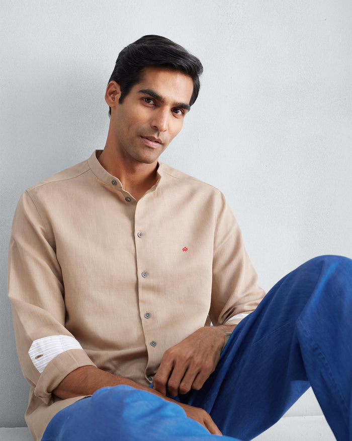 Person wearing a beige Nawab shirt with a Nehru collar and red logomark.