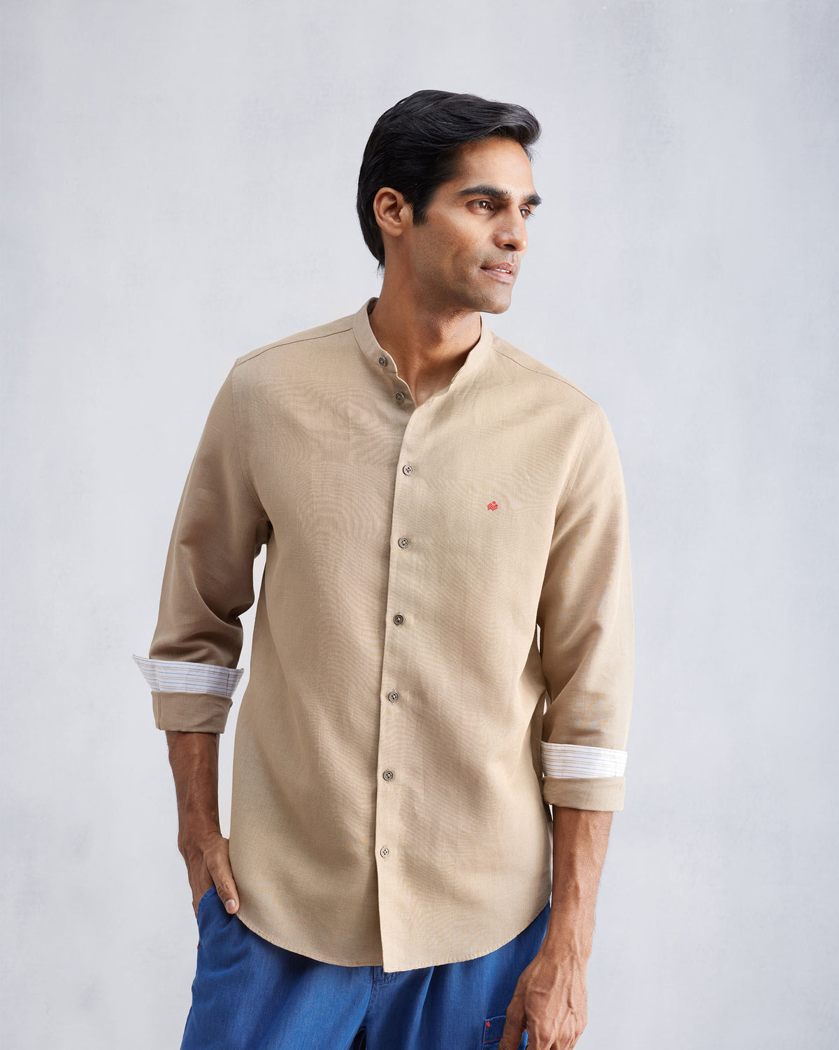 Person wearing a beige Nawab shirt with rolled sleeves showing striped cuff trim.