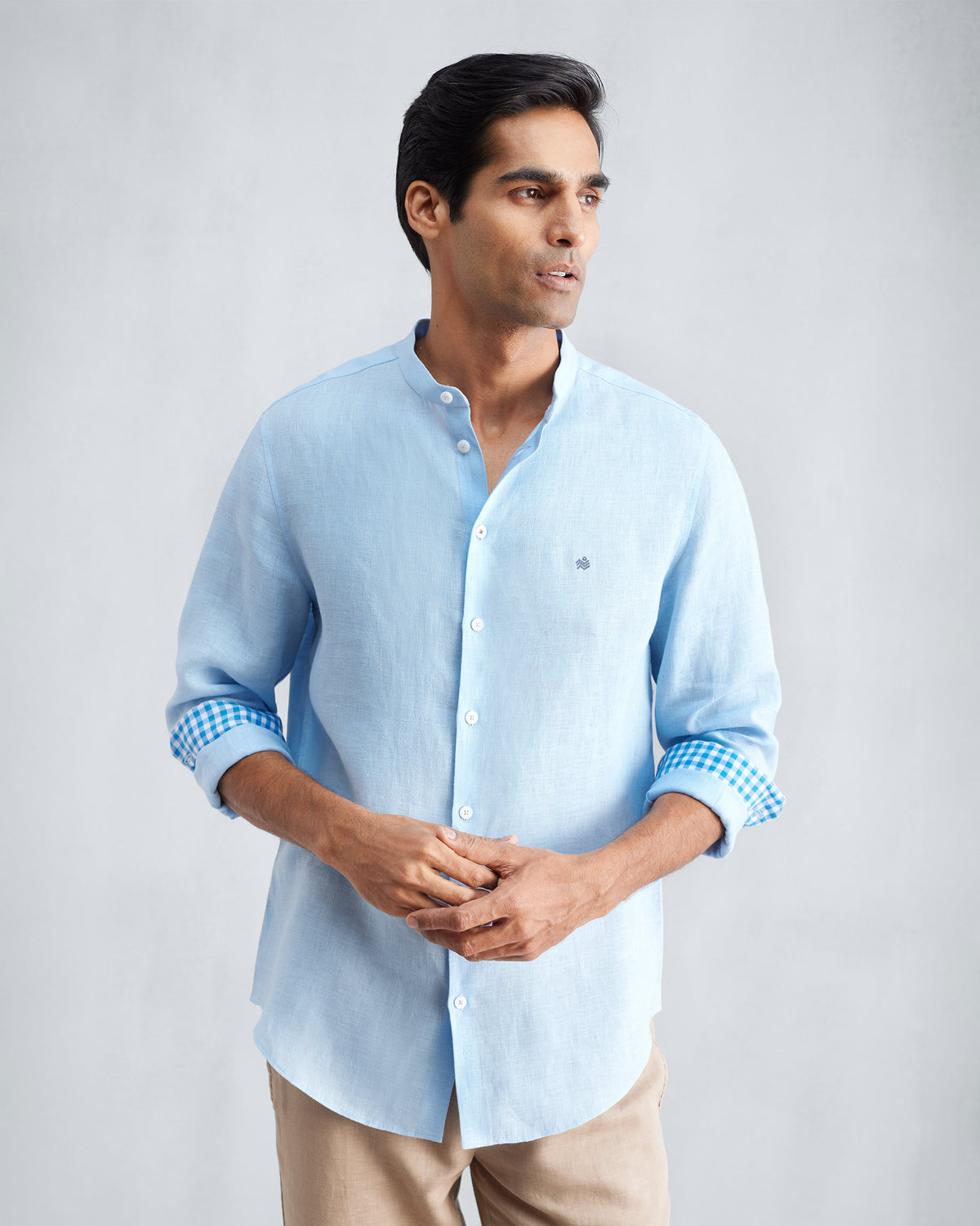 Light blue Nawab shirt with a Nehru collar and gingham cuff lining rolled up.