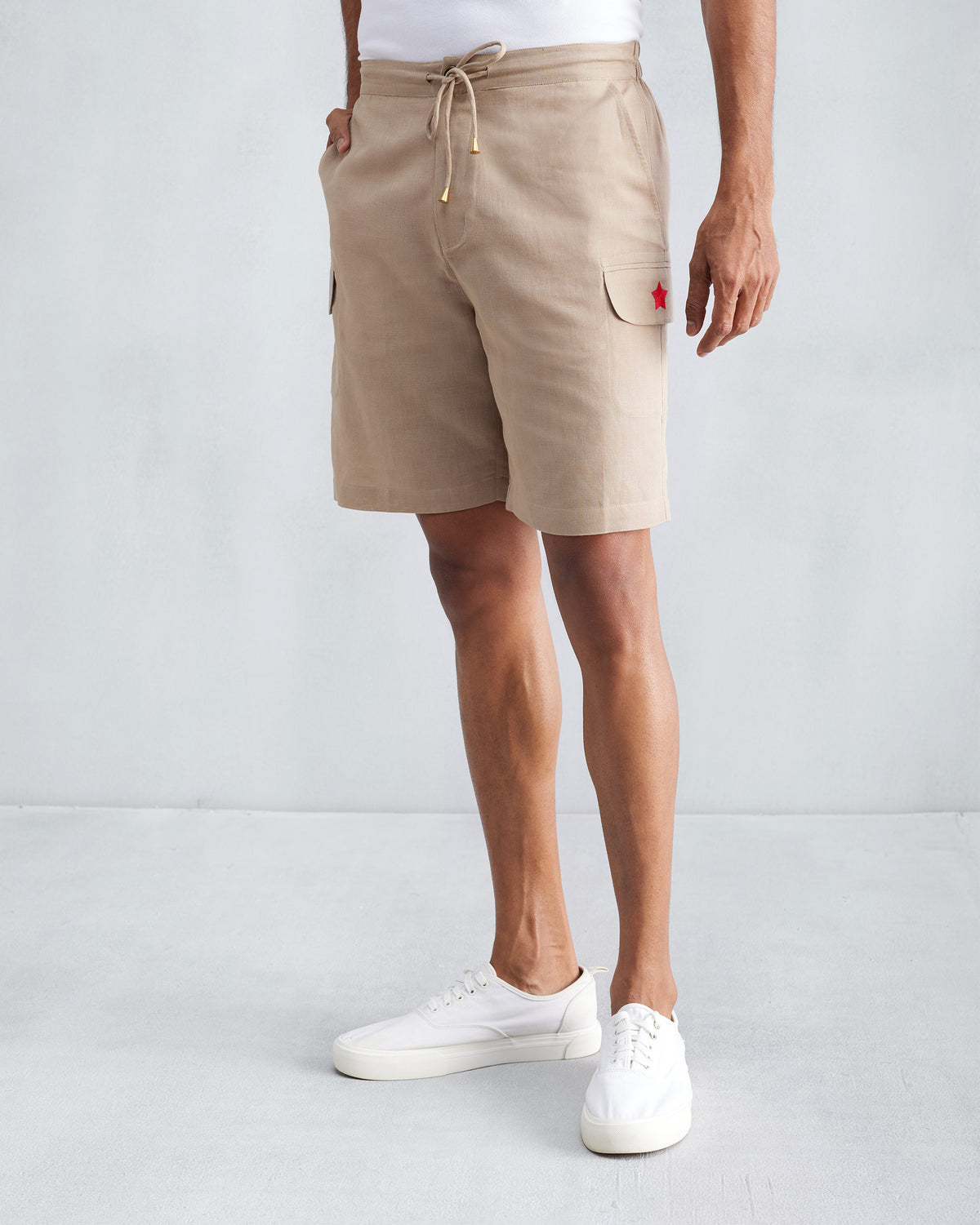 Person wearing beige Classic Shorts with a red star on the pocket.