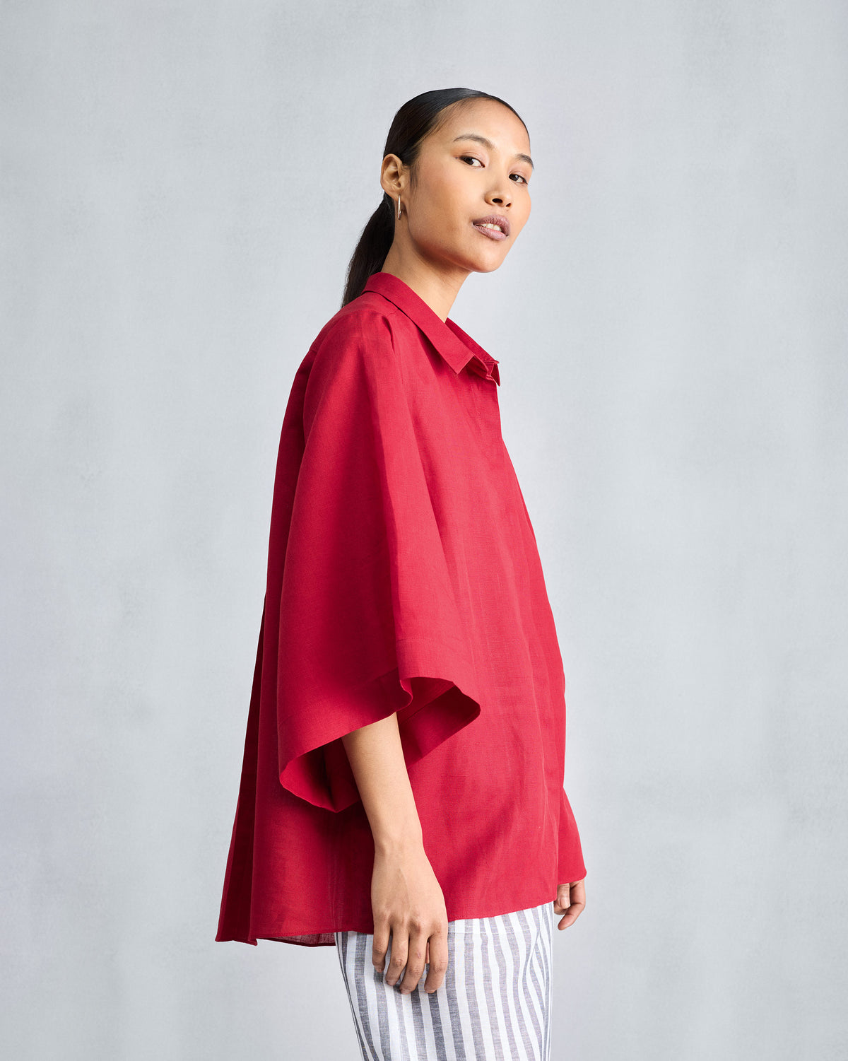 Side view of a red drop armhole shirt worn by a person.