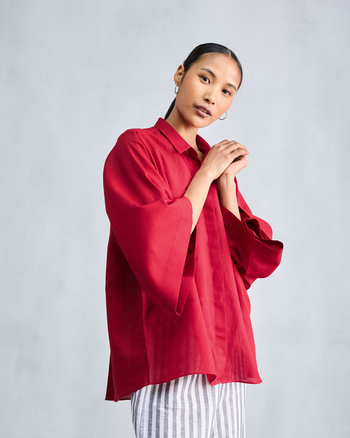 Person wearing a red drop armhole shirt with wide sleeves.