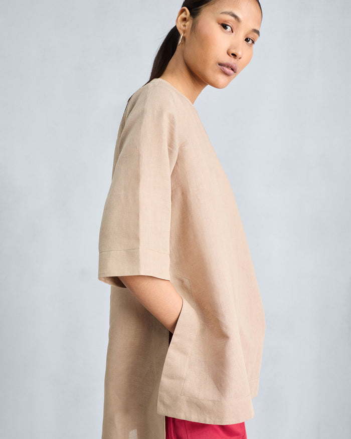 Side view of a beige High Slit Top showing deep side slits and elbow sleeves.