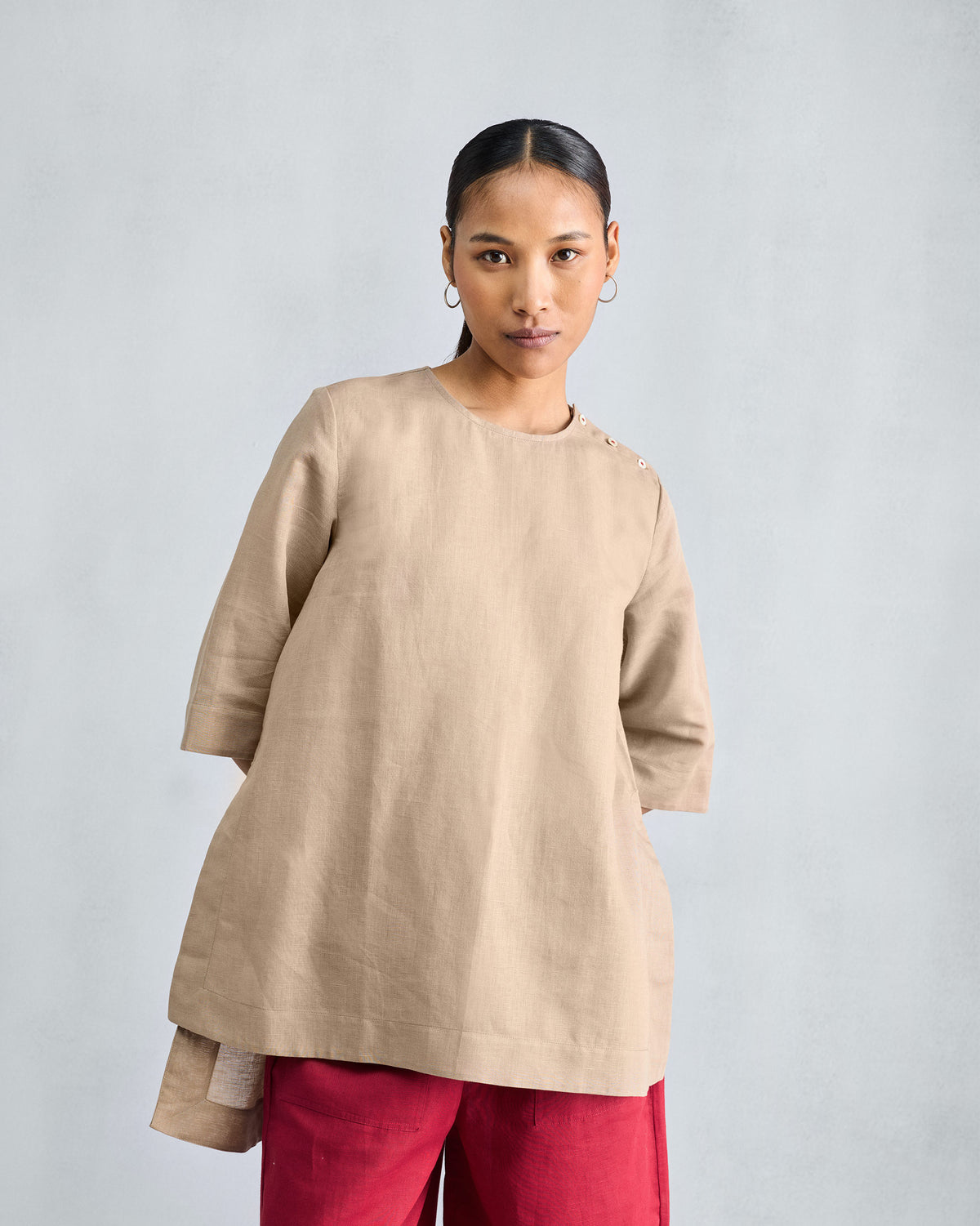 Person wearing a beige High Slit Top with shoulder buttons and wide sleeves.