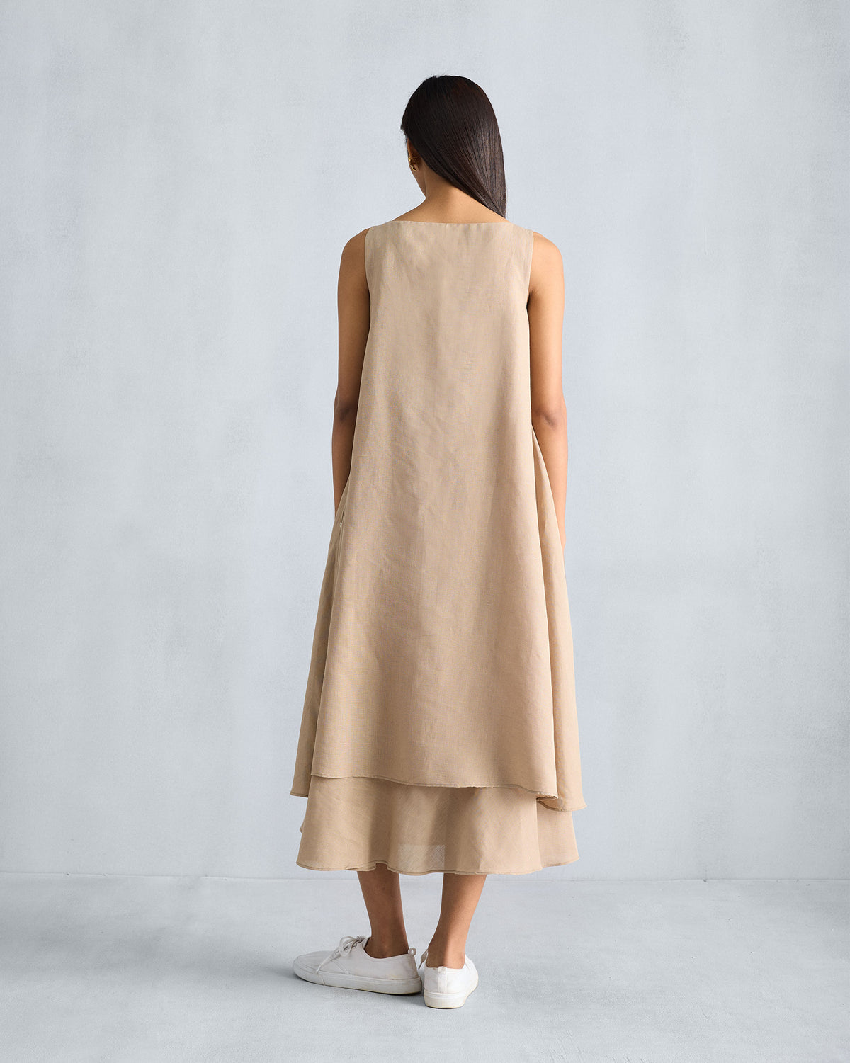 Back of a beige Double Layer Dress with a tiered midi hem.