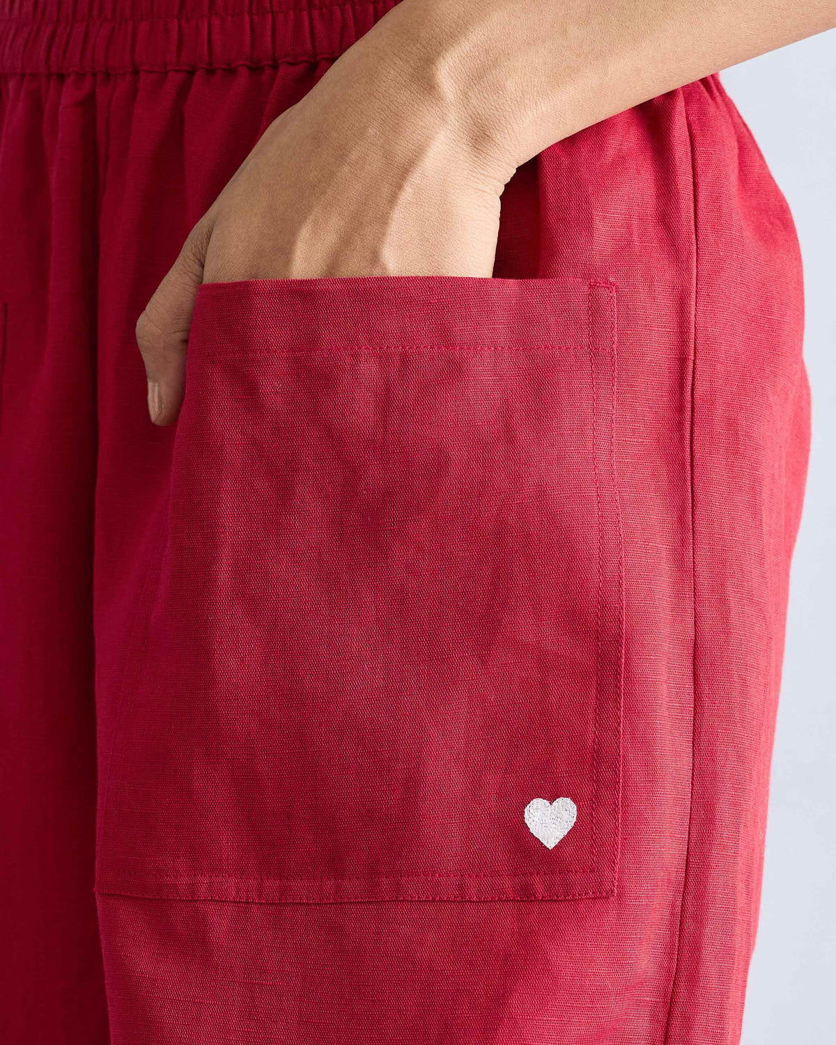 Close-up of red pants with a patch pocket and white embroidered heart.