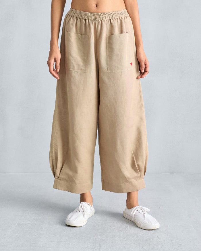 Person wearing beige serene pants with front patch pockets and a red heart.