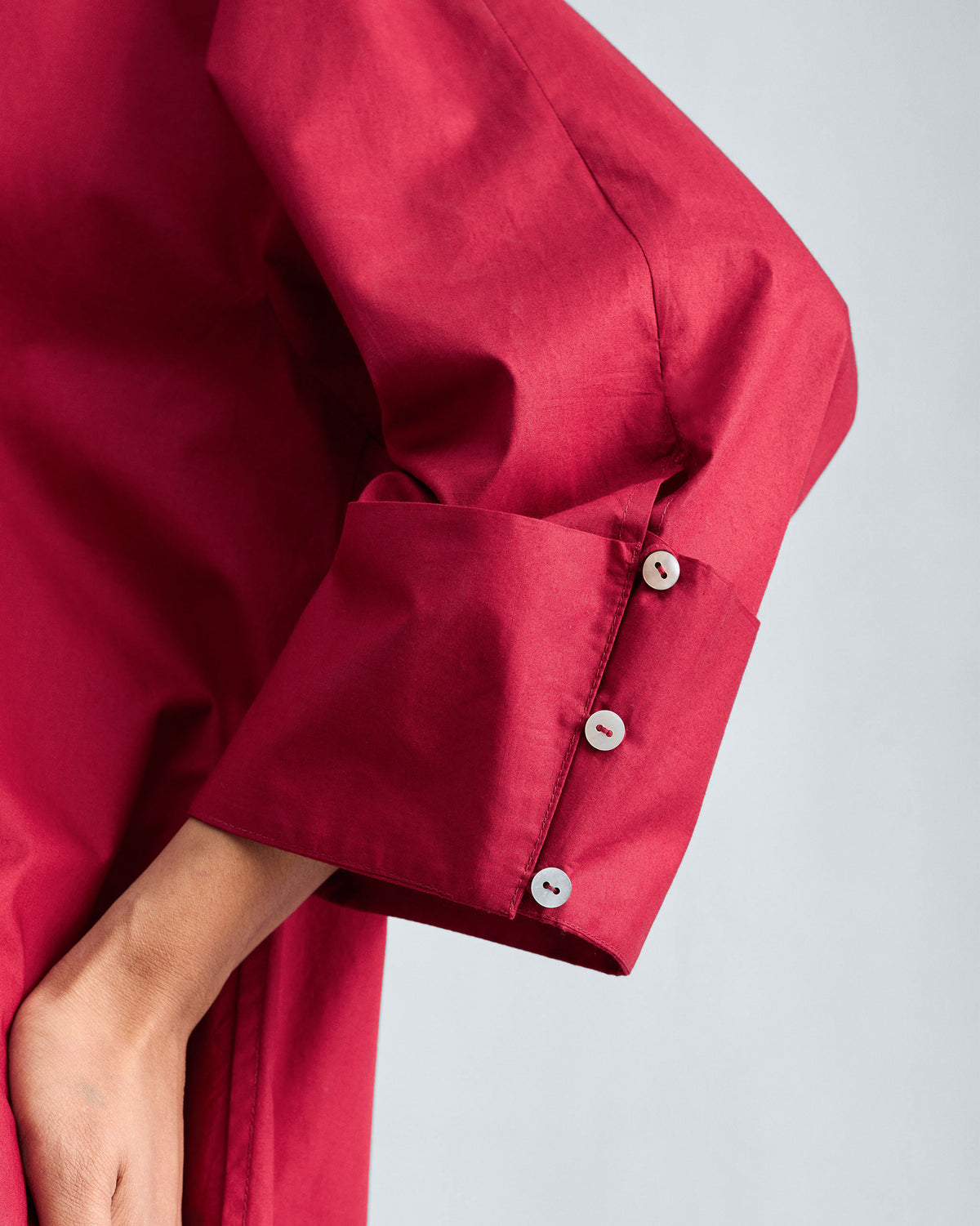 Close-up of a red Cirrus shirt cuff with a row of small white buttons.