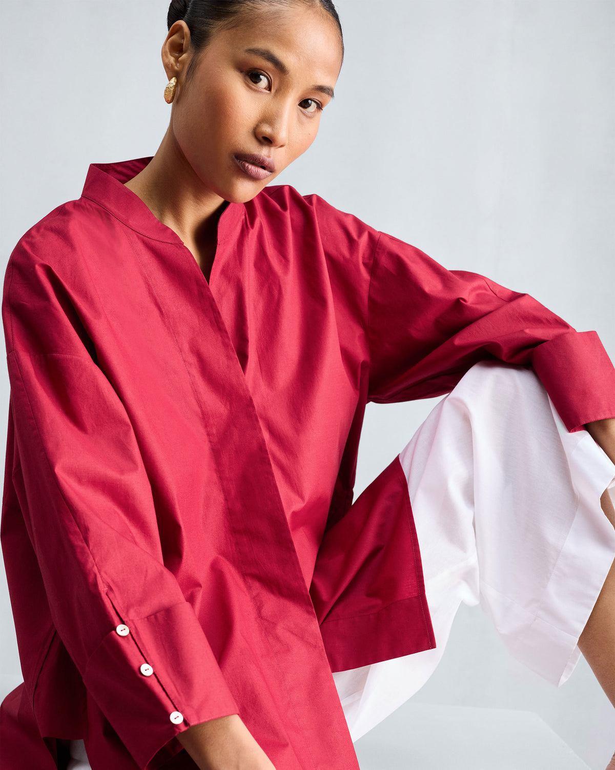 Person wearing a red Cirrus shirt with a V neckline and wide buttoned cuffs.