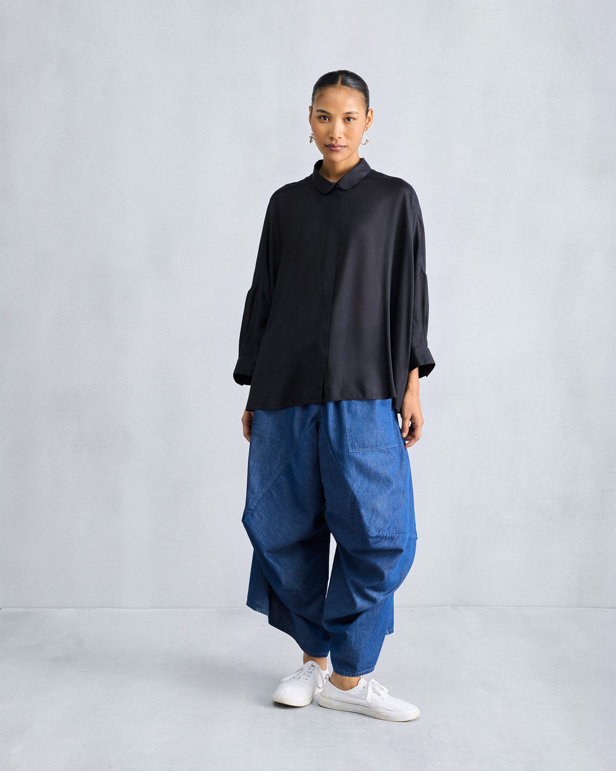 Person wearing a black boxy shirt with a rounded collar and mid-thigh length.