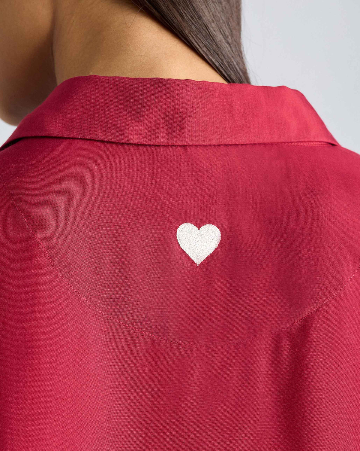 Close-up of a white embroidered heart on a red Boxy shirt.