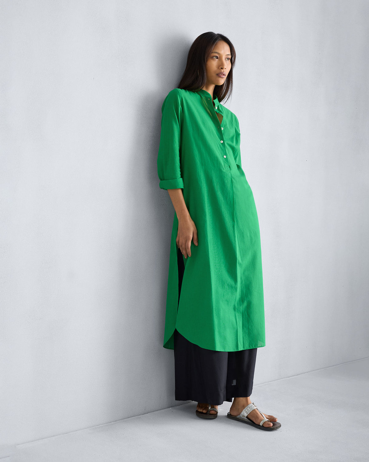 Person wearing a green long kurta with mandarin collar over black trousers.