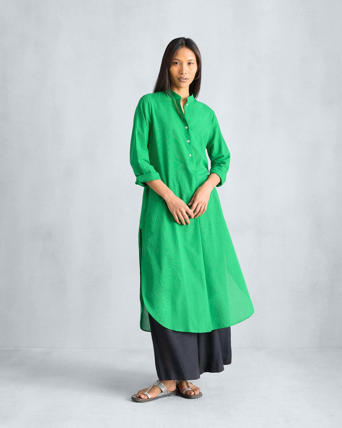 Green long kurta with button placket and curved hem worn with black trousers.