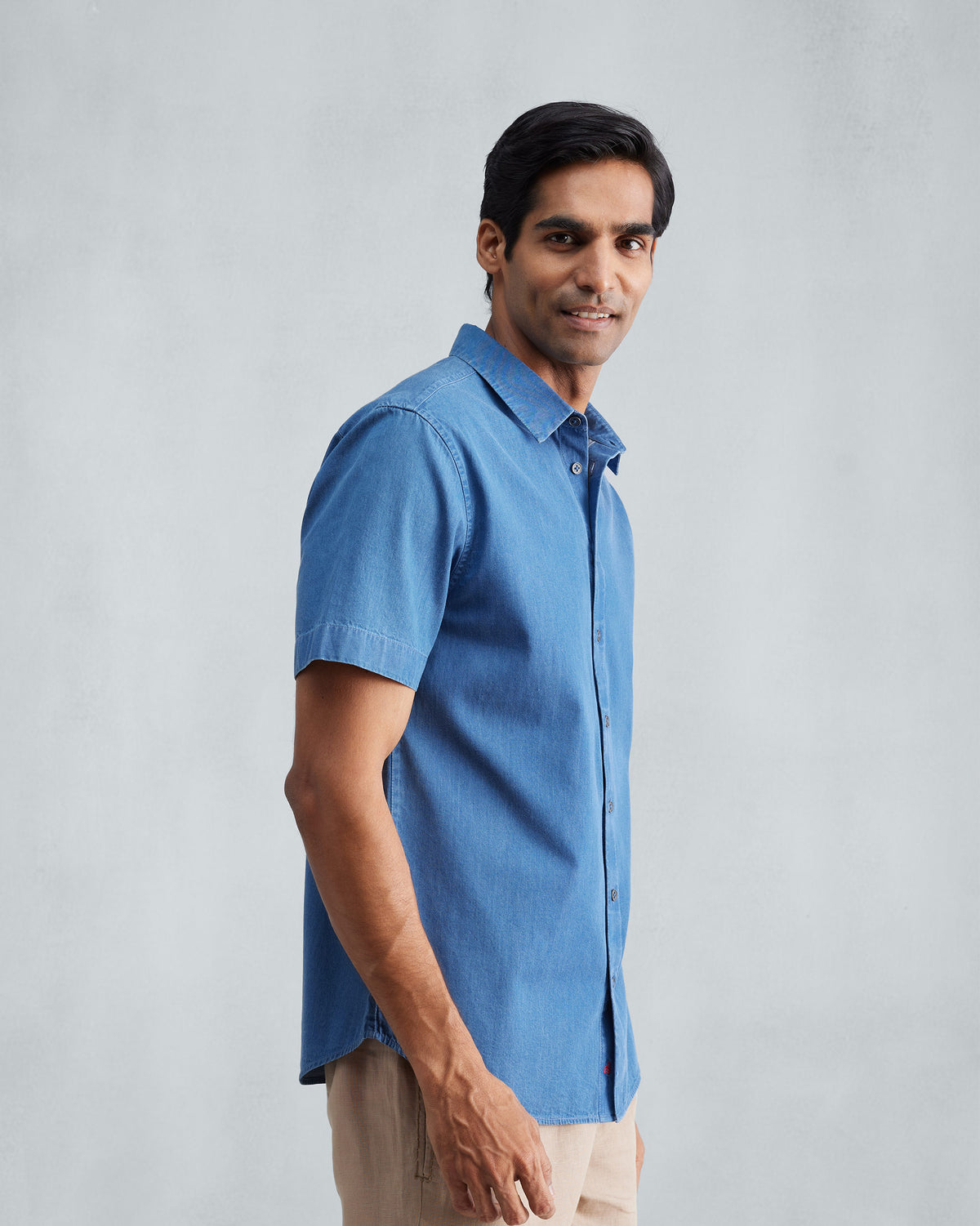 Side view of a denim half sleeve shirt showing the curved hem.