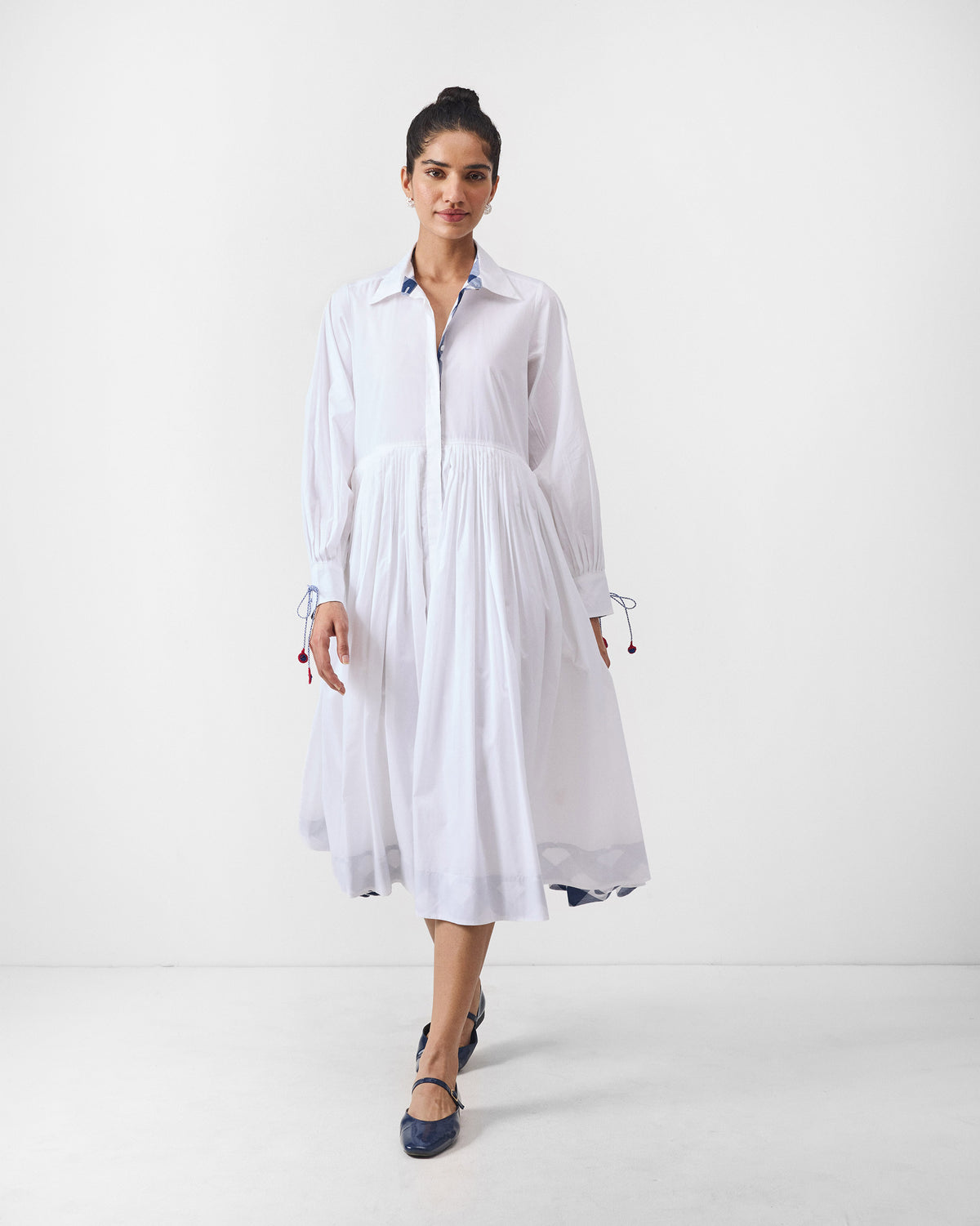 Front of a white Puritsu shirt dress with a pleated midi skirt.