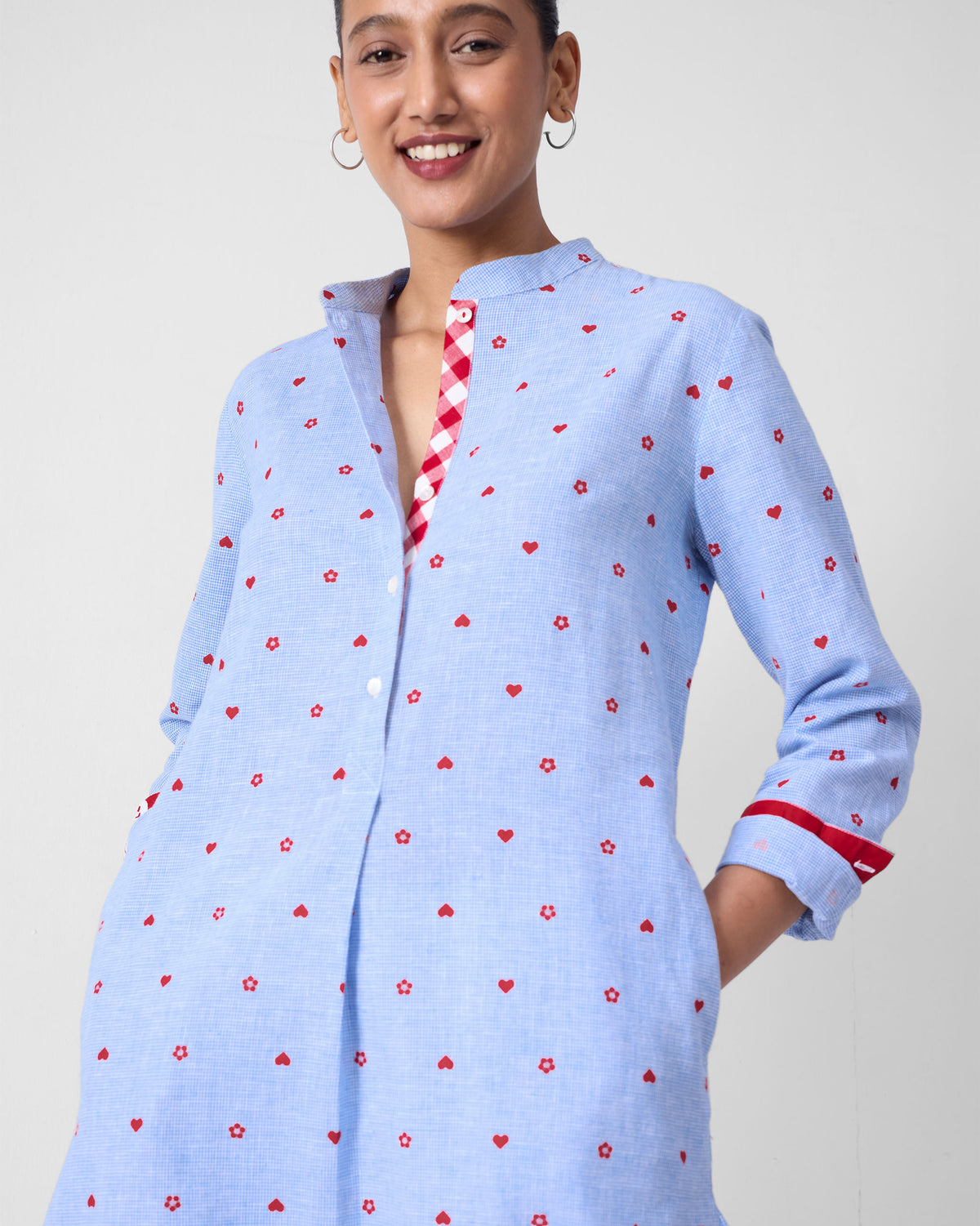 Blue kurta with red motifs, a gingham placket lining, and a red cuff band.