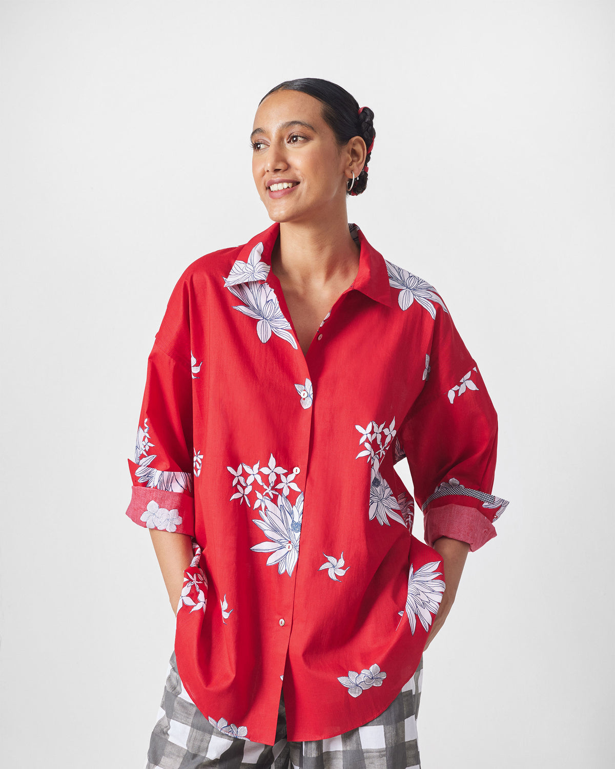 Person wearing a red oversized shirt with white floral print.