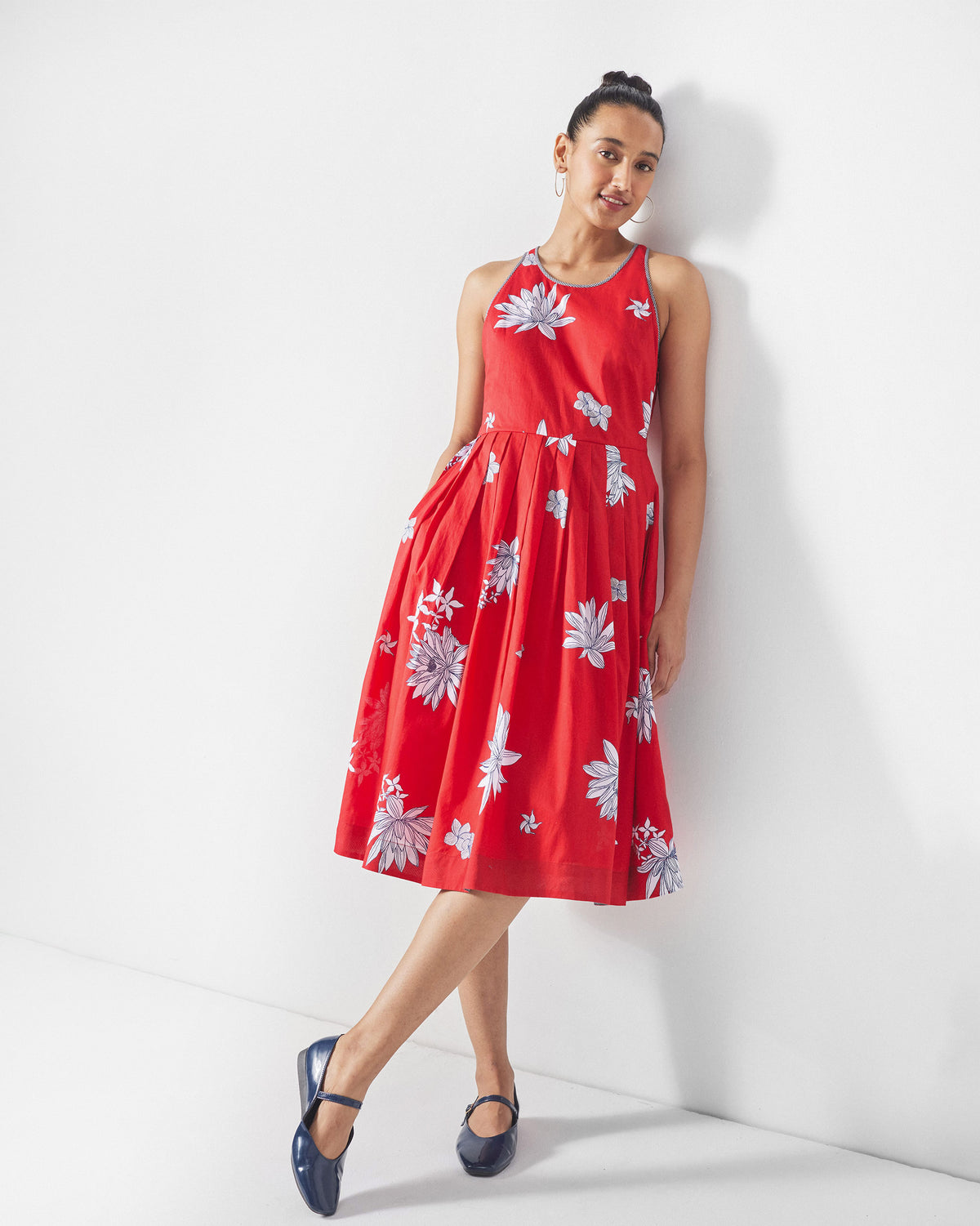 Person wearing a red Kaito Dress with white lotus print and a pleated skirt.