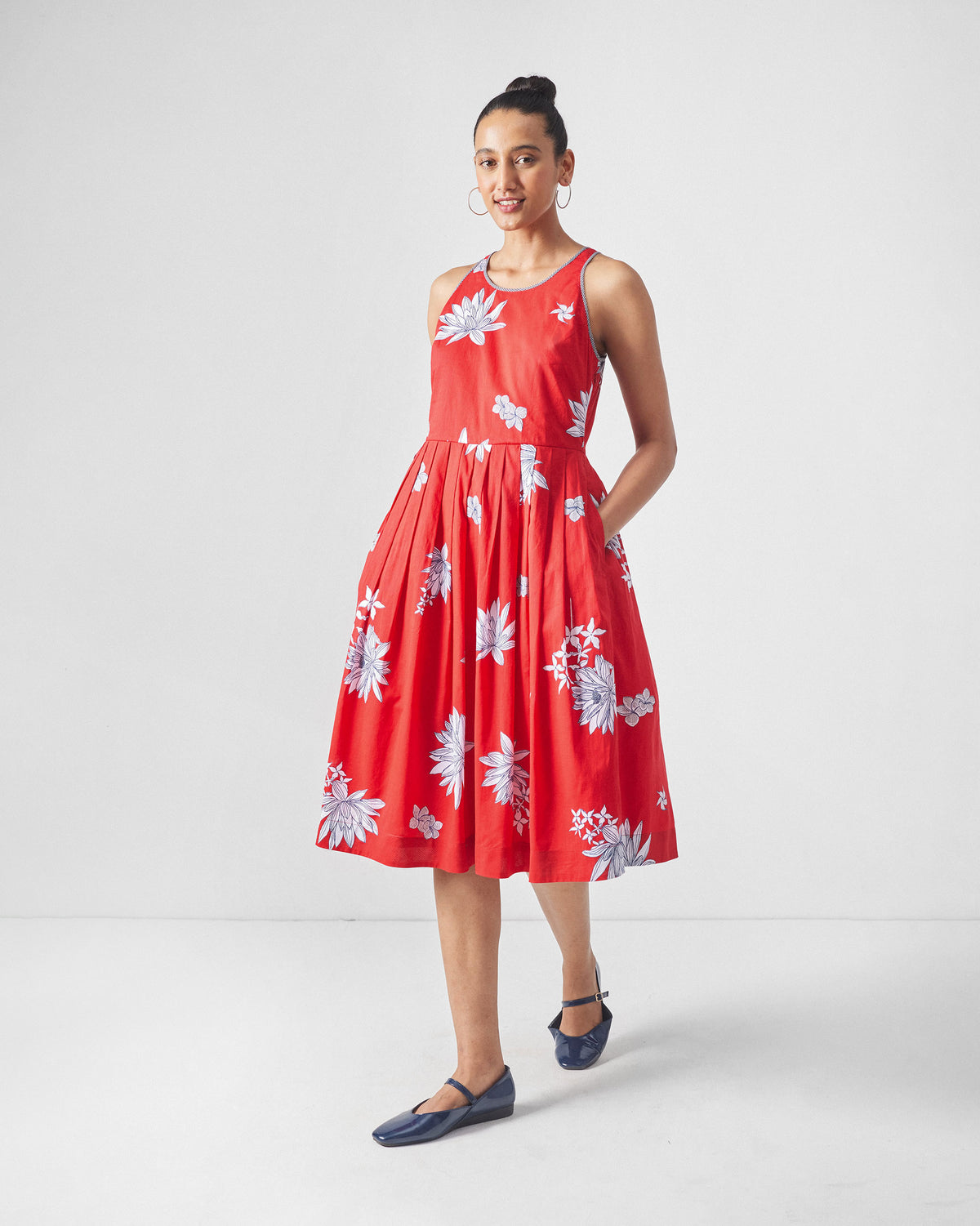 Person wearing a red Kaito Dress with white lotus print and a side pocket.