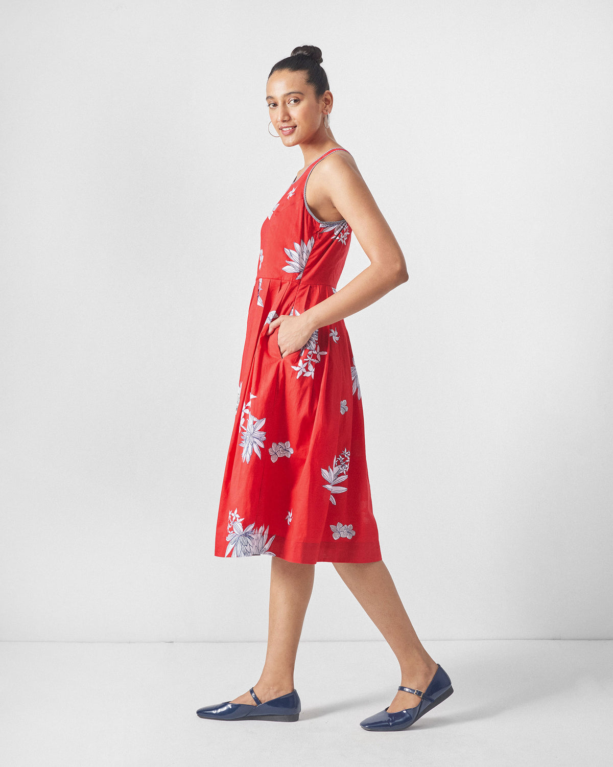 Side view of a red Kaito Dress with white lotus print and a flared skirt.