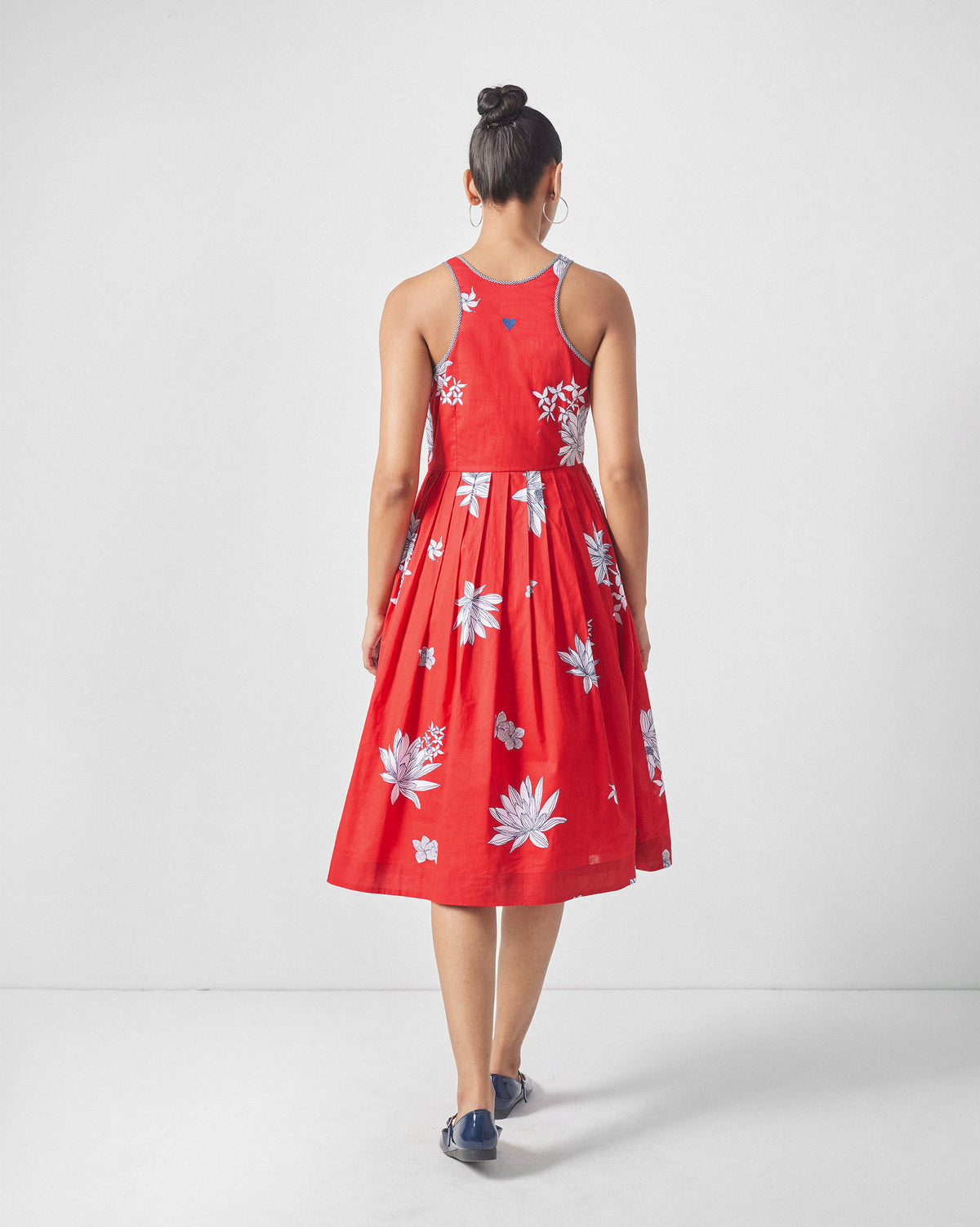 Back of a red Kaito Dress with a blue embroidered heart below the neckline.