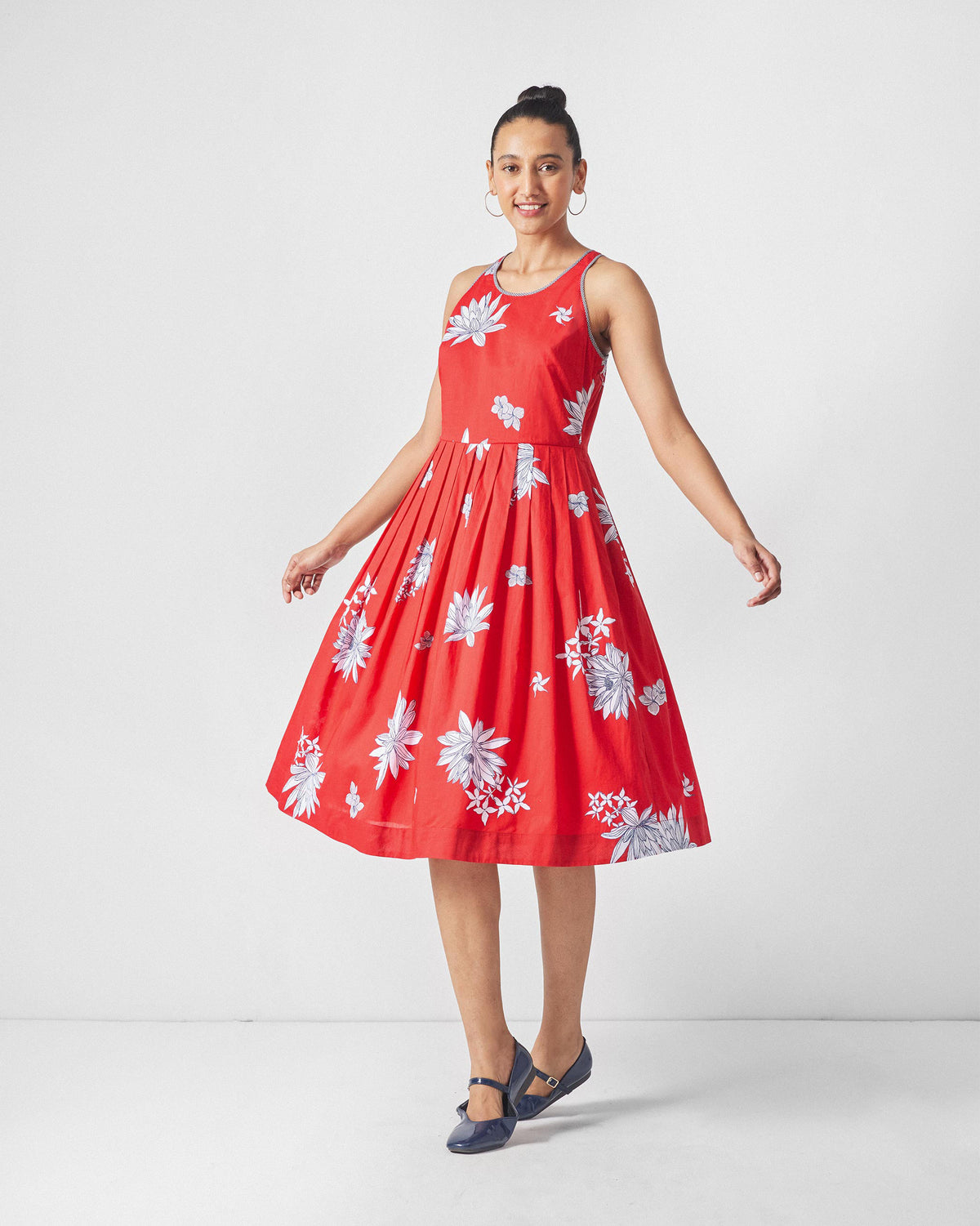 Person wearing a red Kaito Dress with white lotus print and a flared midi skirt.