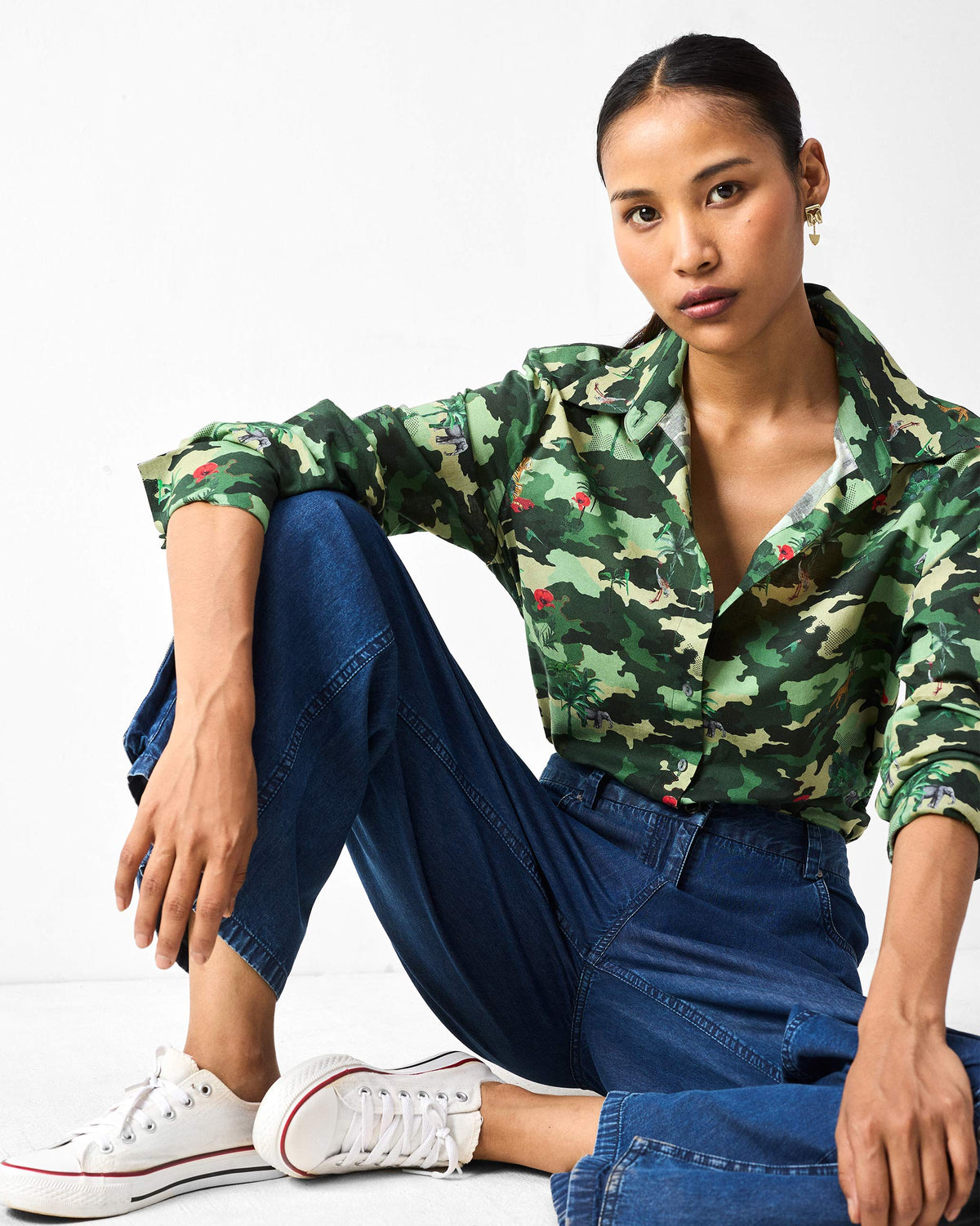 Person wearing a green camouflage Tropico Shirt in a casual seated fit.