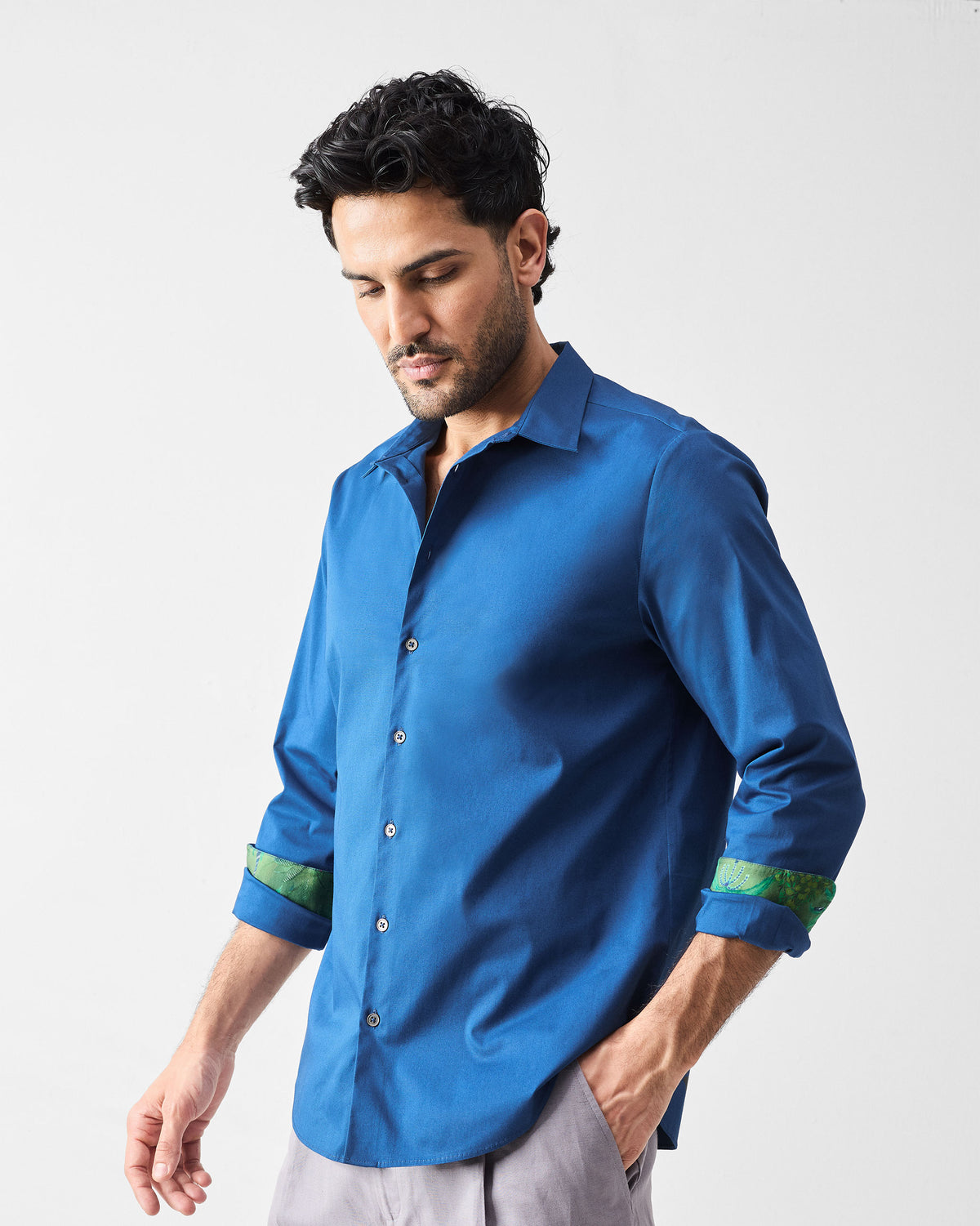 Person wearing a dark blue Hakuna Shirt with rolled sleeves and green leaf lining.