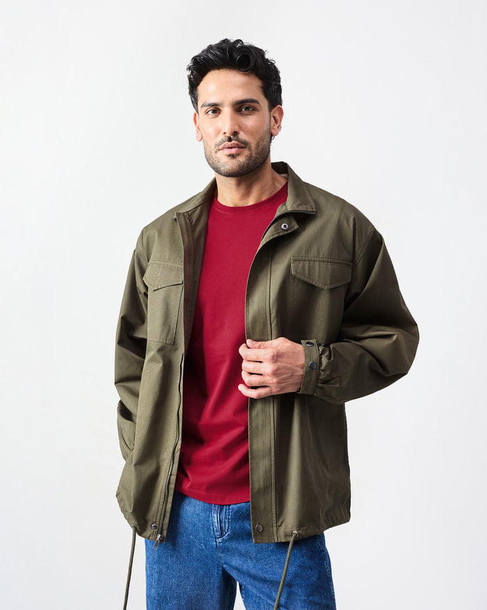 Person wearing an olive utility jacket with flap chest pockets.