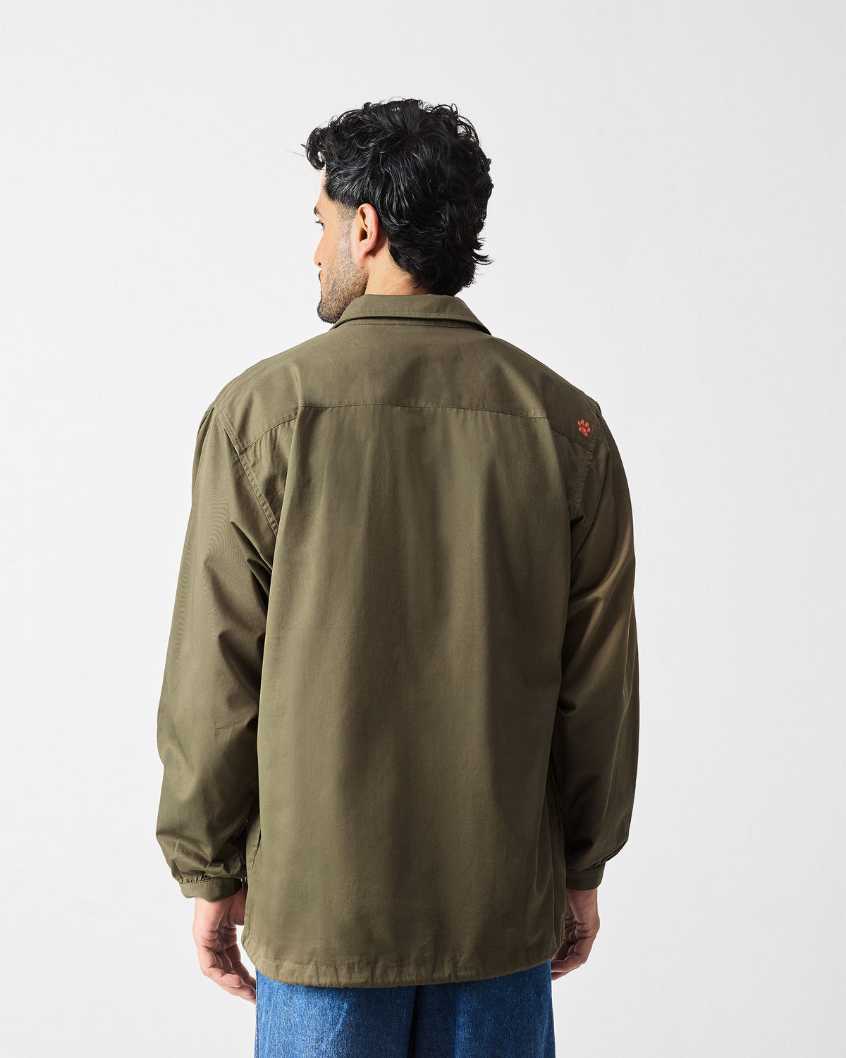 Back of an olive utility jacket with a small orange paw embroidery.